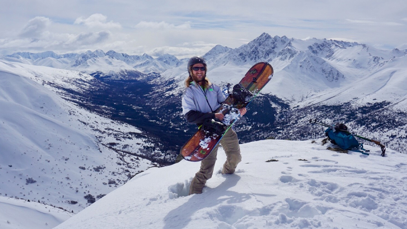 Man standing on a mountain with a snowboard