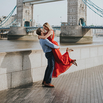 Man embraces woman in front of London bridge