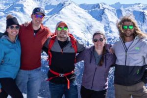 Group of skiers pose for photo in front of mountains