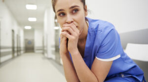 Worried and stressed nurse sitting on corridor