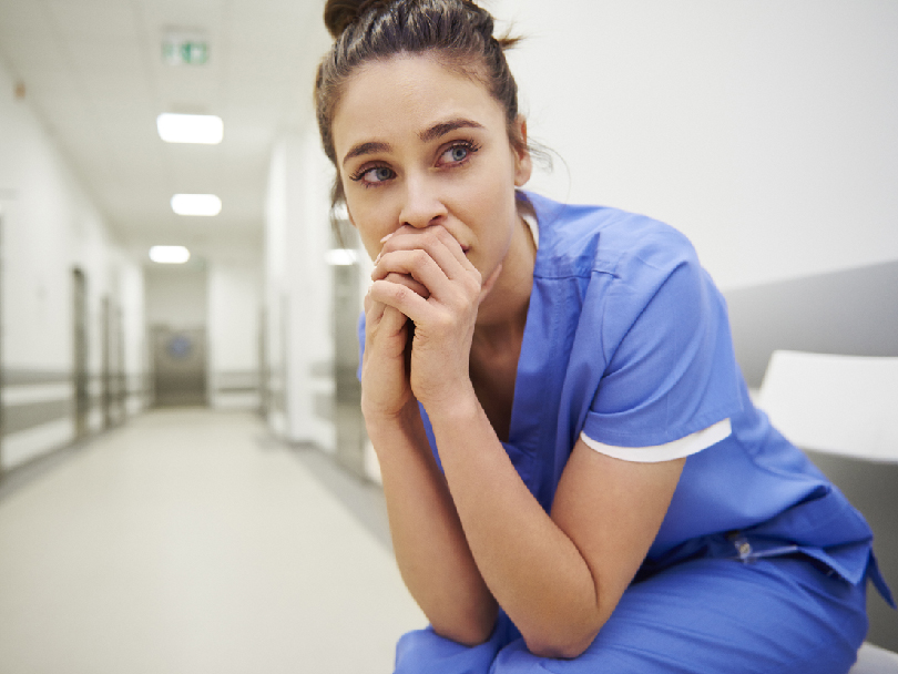 Worried and stressed nurse sitting on corridor