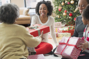 Woman gives a gift to another woman surrounded by family