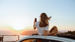 Picture of woman taking a picture of the sunset through her car roof